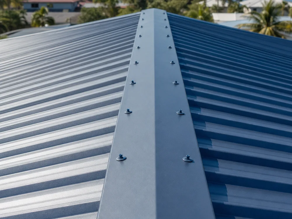 Repaired metal roof ridge cap with closure strips and evenly spaced cap fasteners